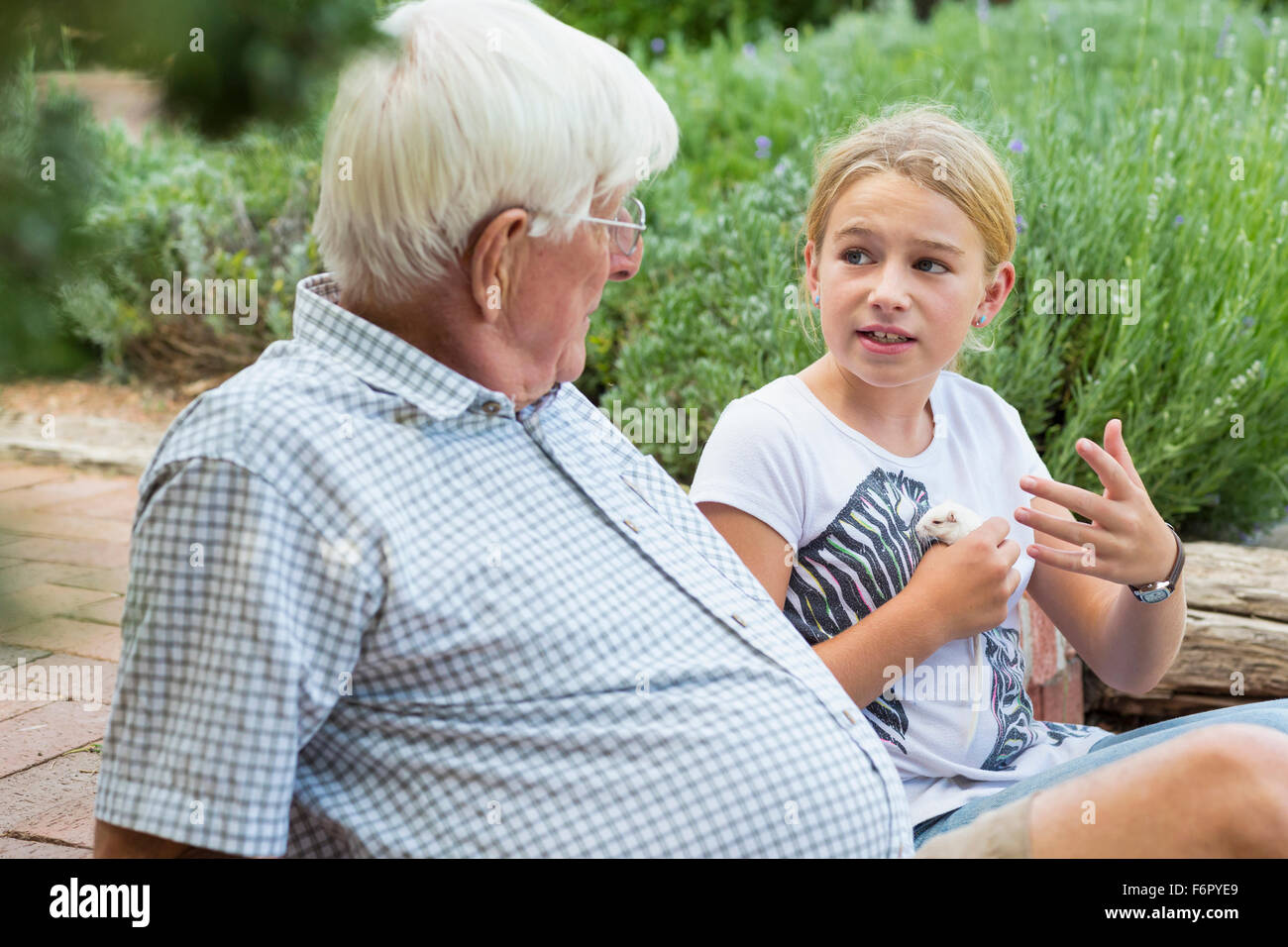 Kaukasische Großvater und Enkelin sprechen im Garten Stockfoto