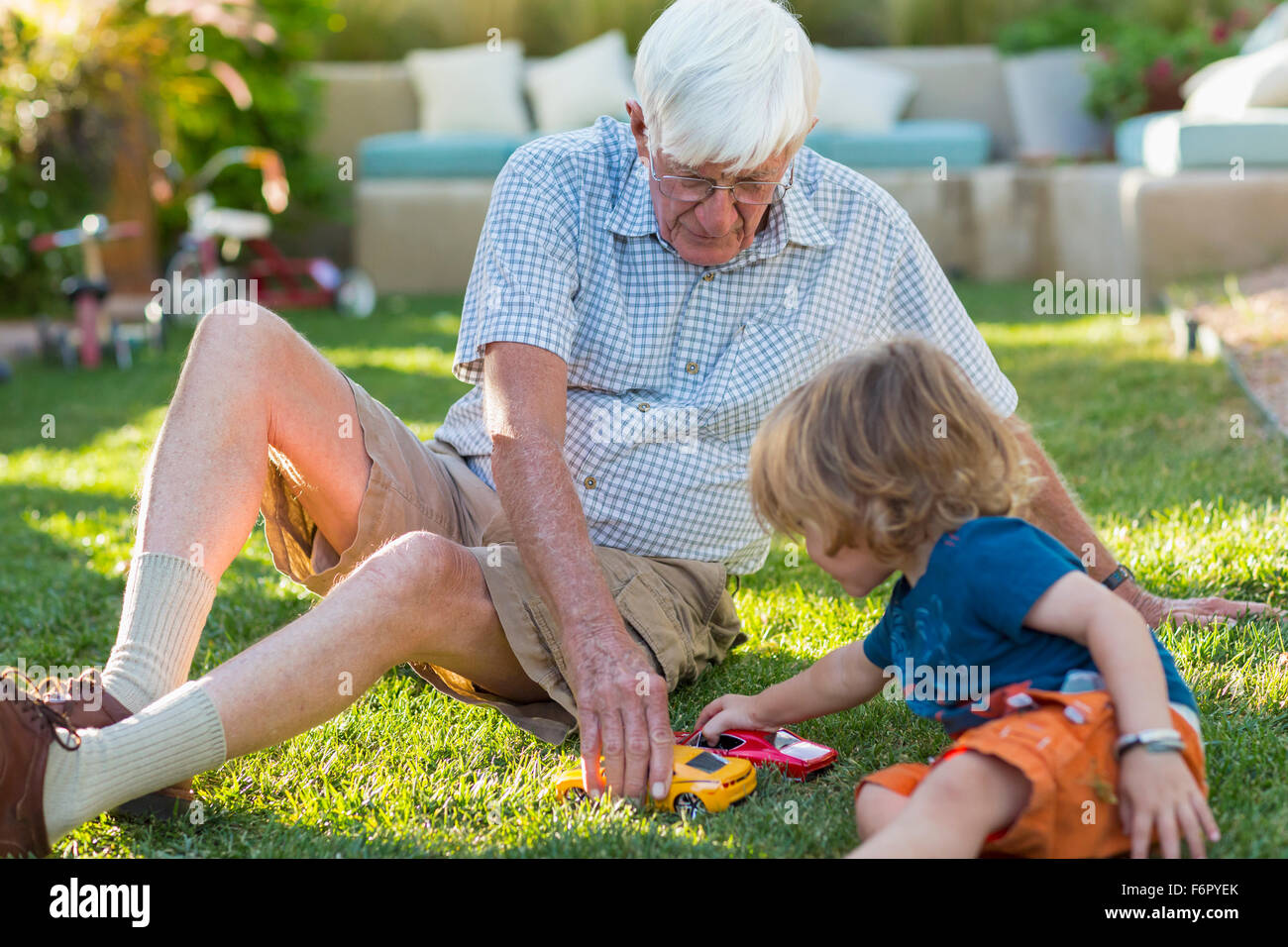Kaukasische Großvater und Enkel spielen auf Rasen Stockfoto