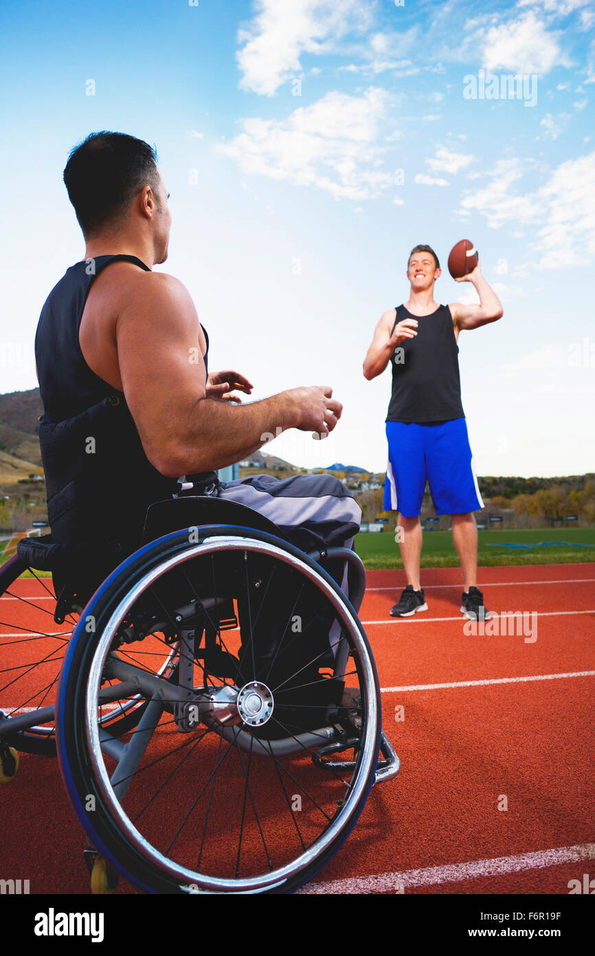 Querschnittgelähmte Sportler im Rollstuhl werfen Kugel mit Freund Stockfoto