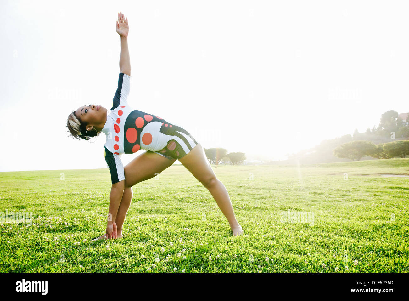 Schwarze Frau praktizieren Yoga im Feld Stockfoto