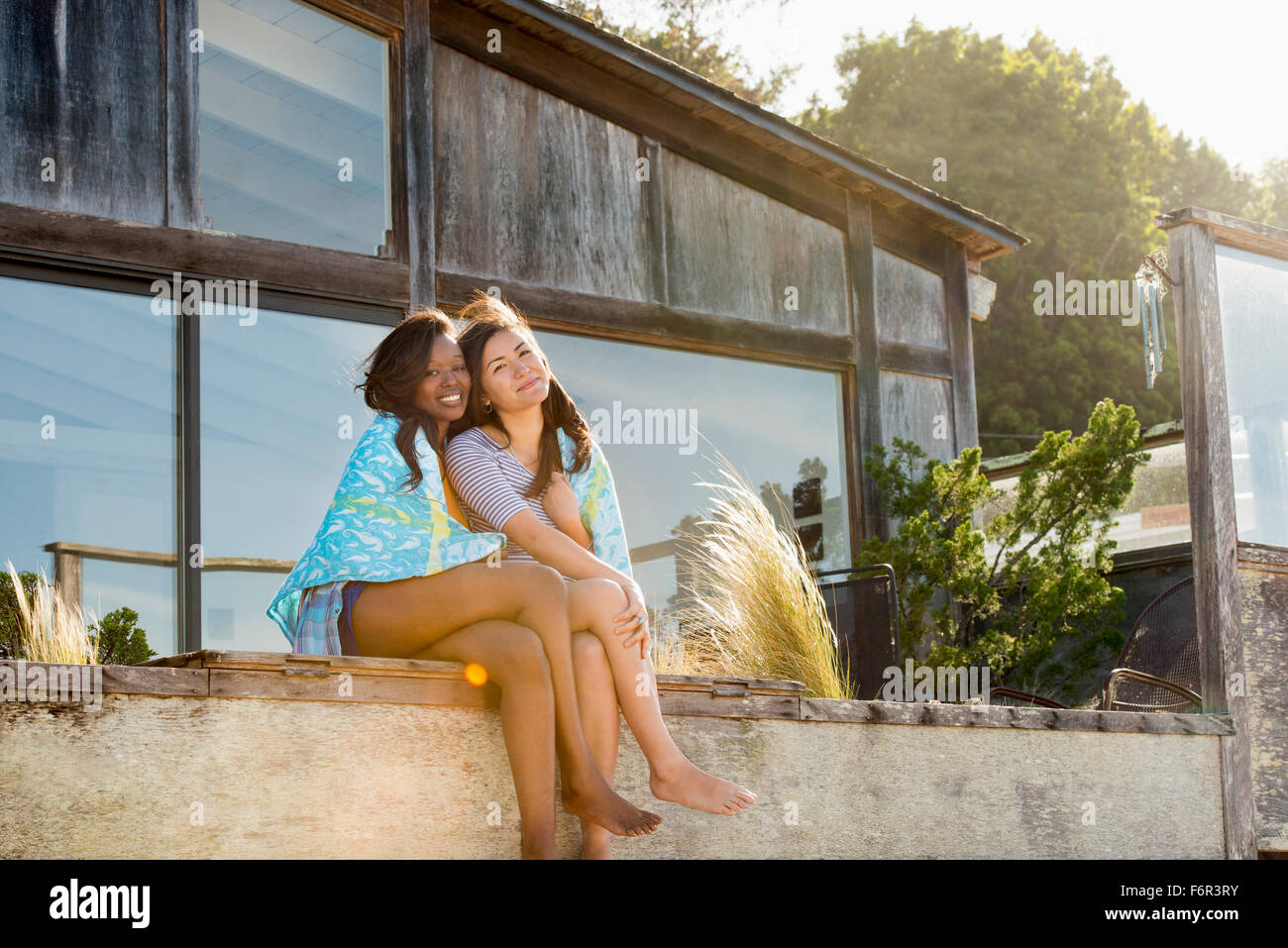 Lächelnde Frauen umarmen im Hinterhof Stockfoto