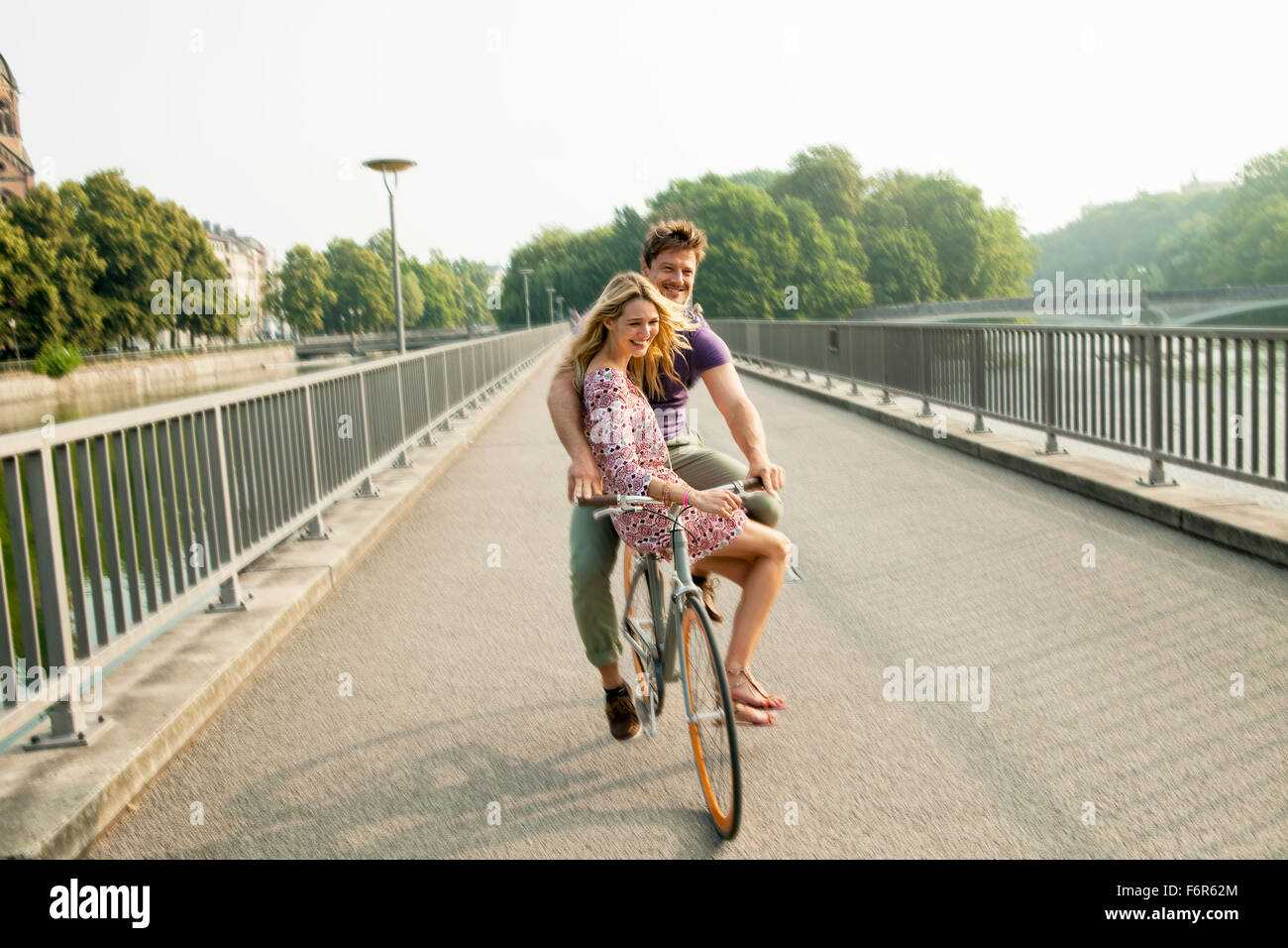 Junges Paar Reiten Fahrrad auf Stadtbrücke Stockfoto