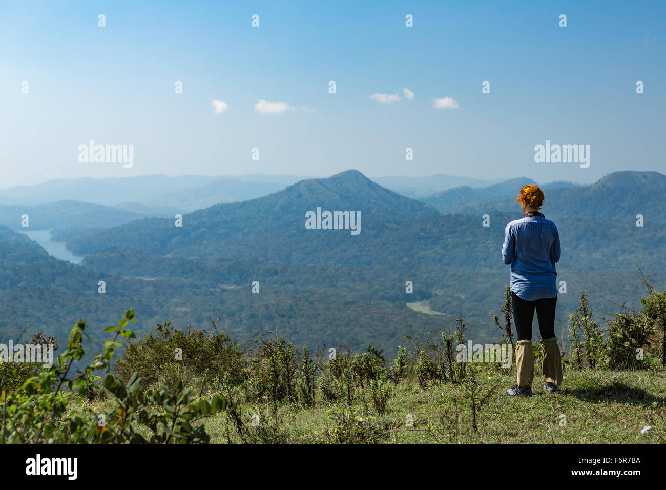 Junge Frau Betrachtung mit roten Haaren blickt auf eine verträumte Landschaft mit grünen Bergen in Kumily in der Region Kerala in th Stockfoto