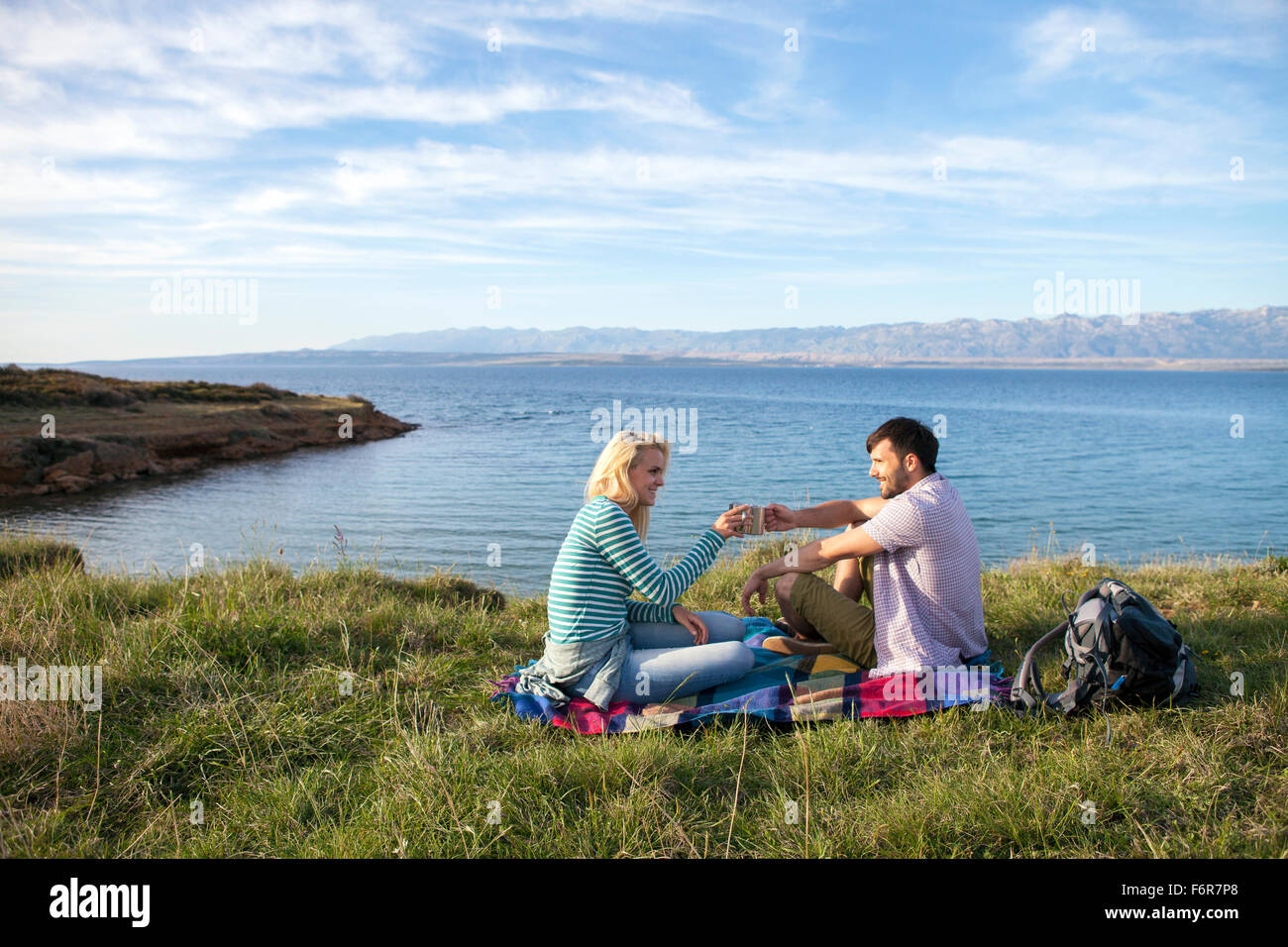 Junges Paar mit einem Picknick am Ufer Stockfoto