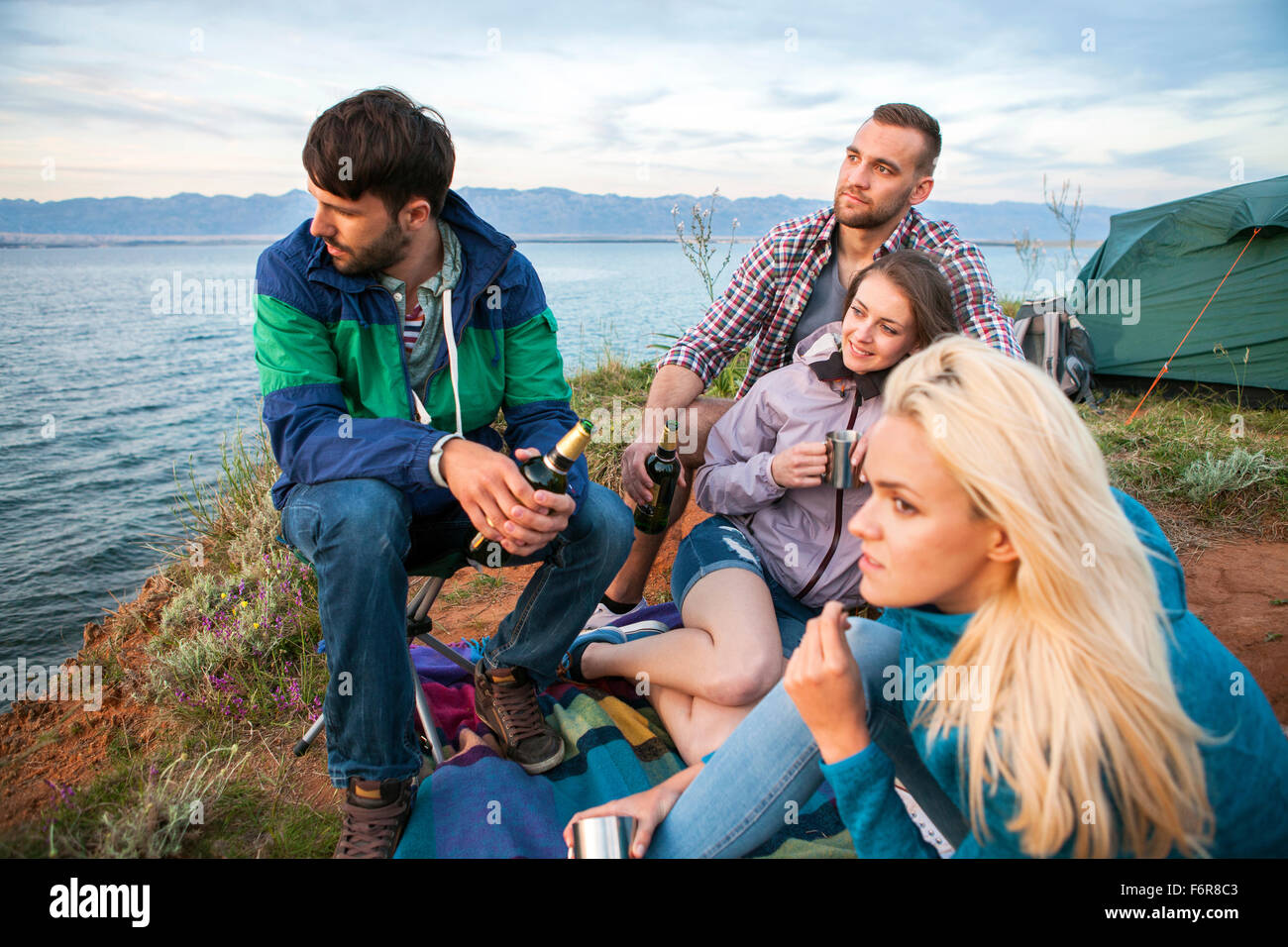Gruppe von Freunden auf Campingplatz mit Blick auf Meer Stockfoto