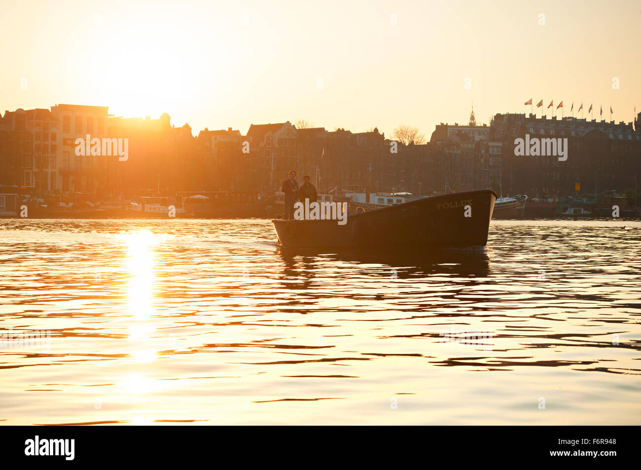 Menschen während der Bootsfahrt bei Sonnenuntergang auf einem Kanal von Amsterdam. Stockfoto