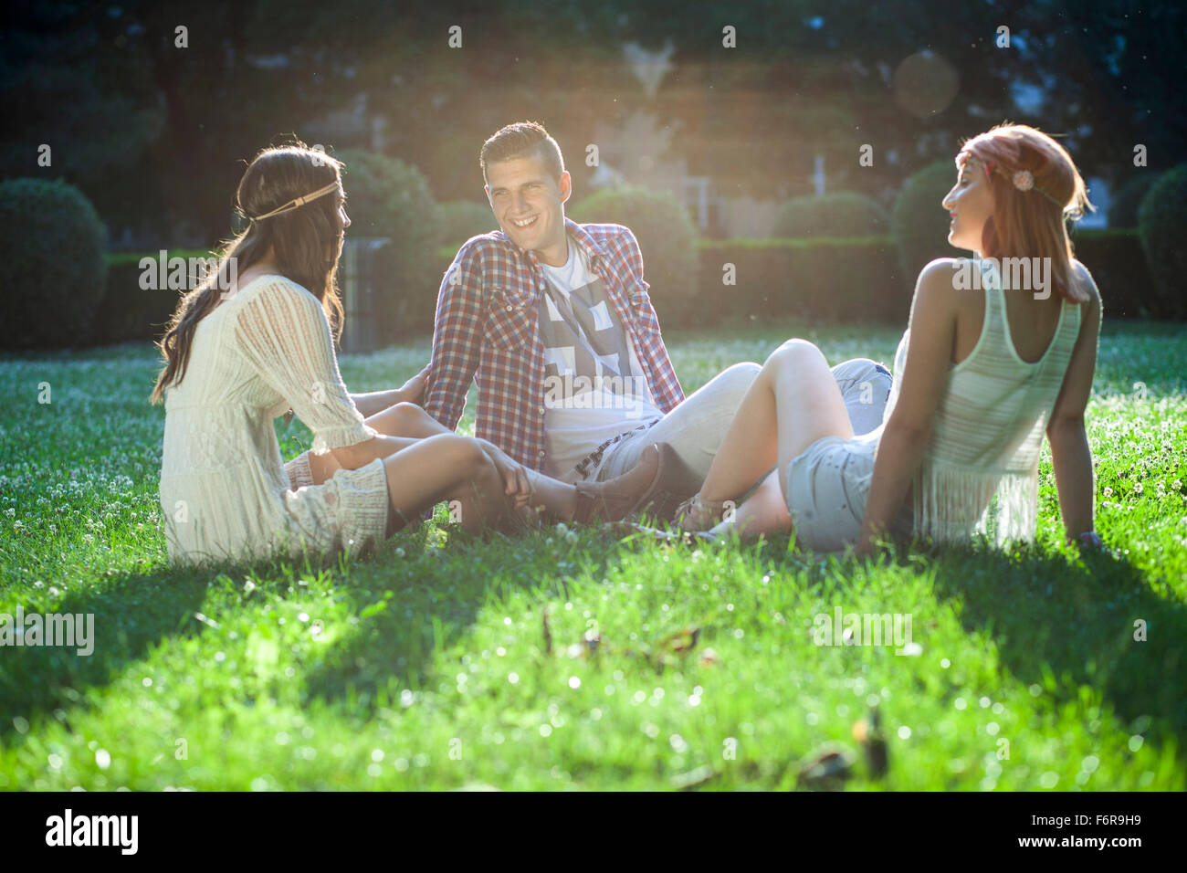 Junge Menschen im Hippie Stil Mode sitzen auf der Wiese Stockfoto