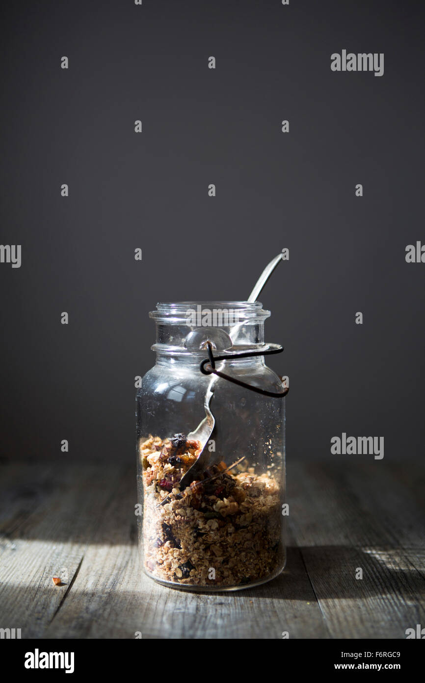 Glas mit hausgemachtem Müsli mit Nüssen, Samen, Rosinen & Preiselbeeren mit Löffel Stockfoto