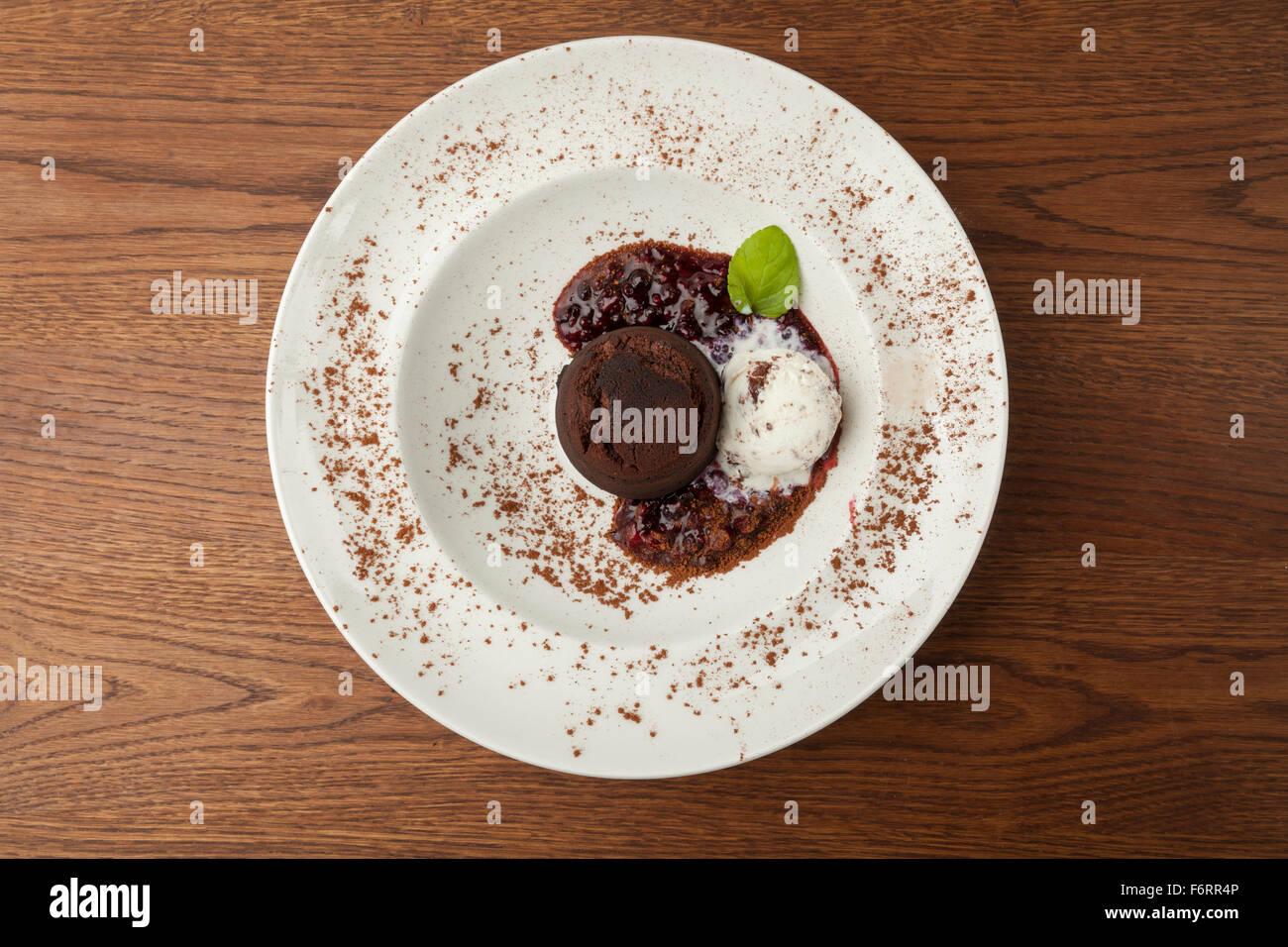 Schokoladenkuchen mit Eis und gekrönt mit Beeren in einem weißen Teller serviert Stockfoto