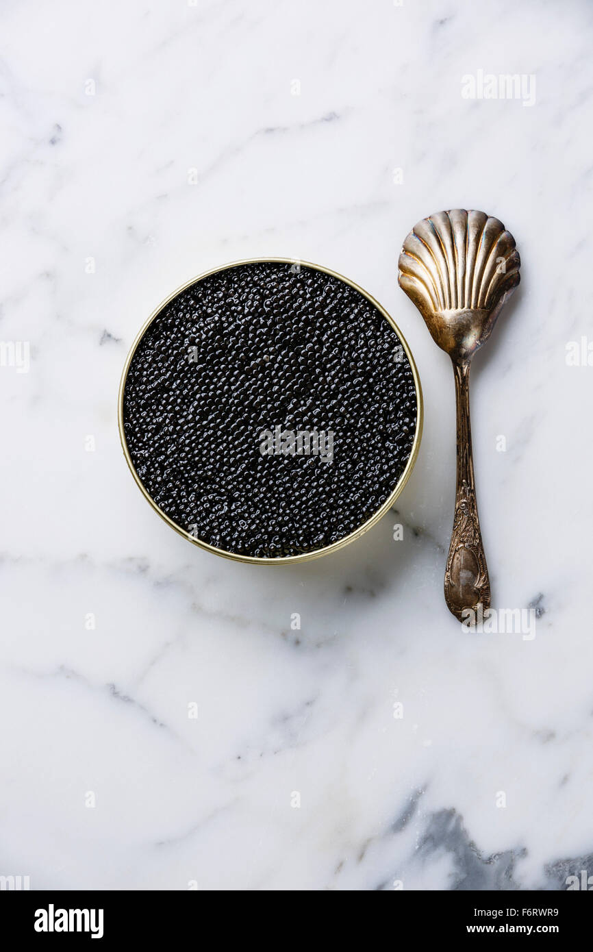 Schwarz von Störkaviar in Can und Löffel auf weißem Marmor Hintergrund Stockfoto