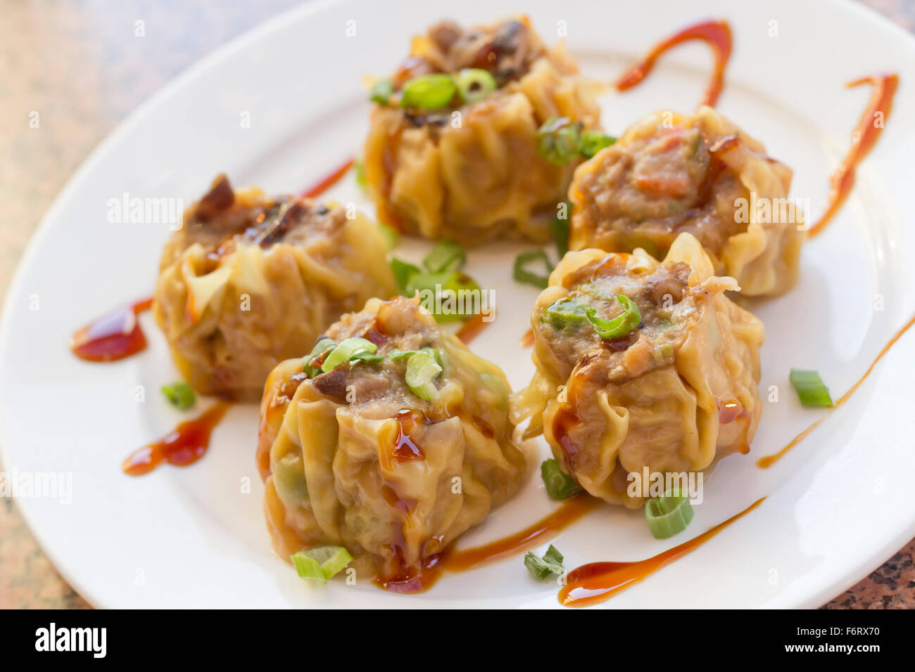 Köstliche chinesische Dim-Sum-Knödel, garniert mit Frühlingszwiebeln und süßer Soße Stockfoto