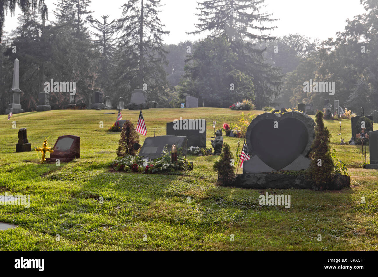 Leere Gräber auf dem Friedhof in den frühen Morgenstunden Stockfoto