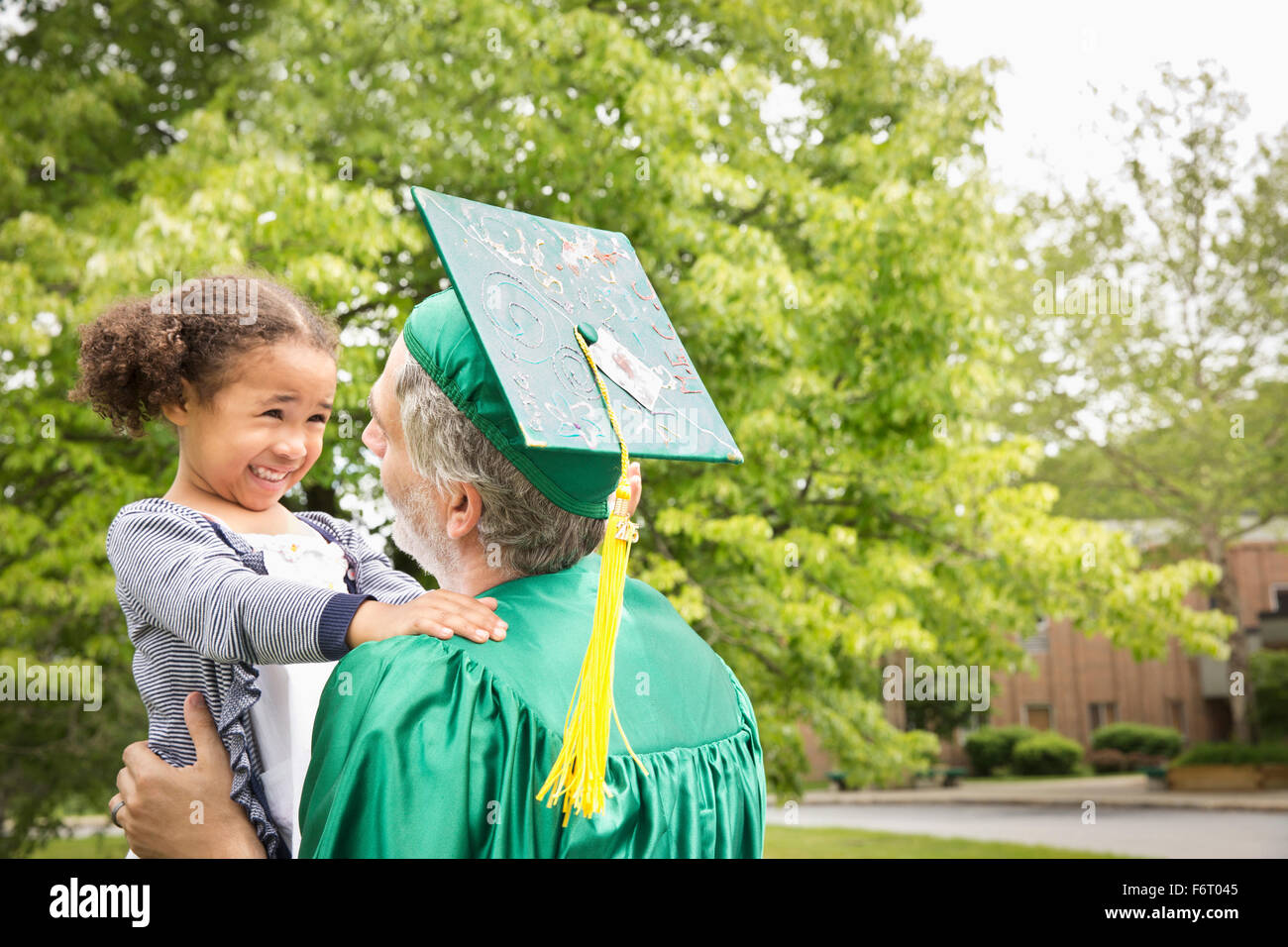 College-Absolvent Vater umarmt Tochter Stockfoto