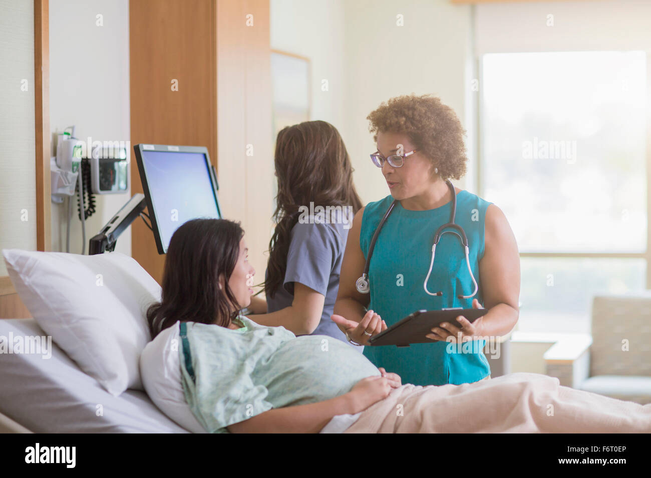 Arzt im Gespräch mit schwangeren Patienten im Krankenzimmer Stockfoto