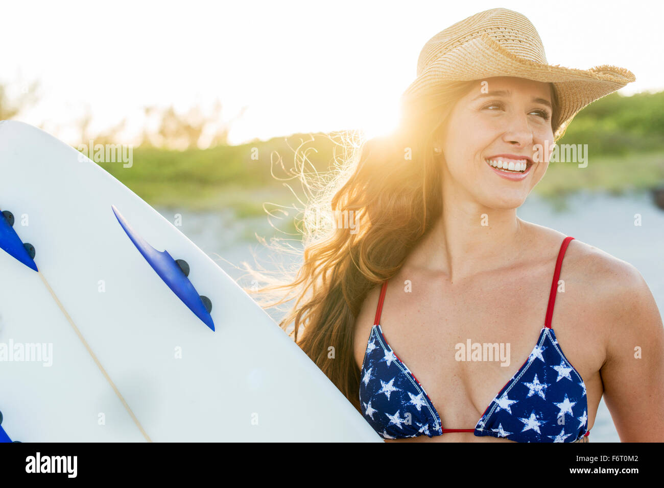 Hispanic Frau mit Surfbrett am Strand Stockfoto