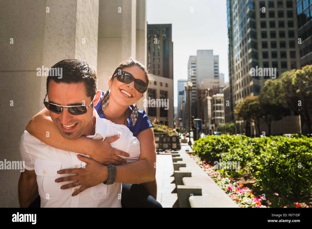 Hispanic Mann mit Freundin Huckepack in Stadt Stockfoto