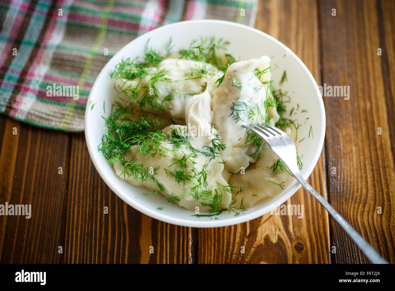 Gekochte Teigtaschen mit saurer Sahne und dill Stockfoto