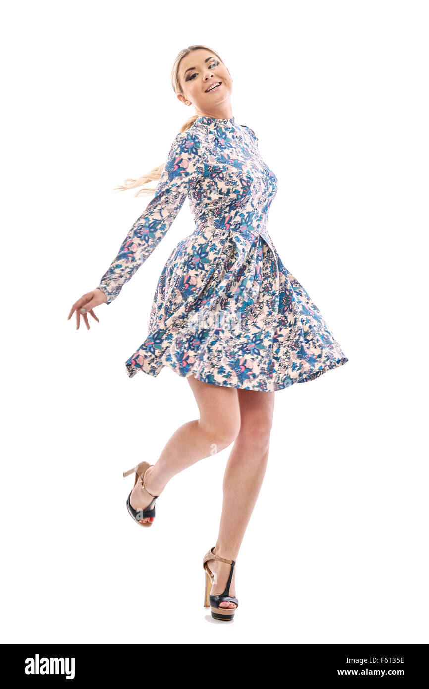 Langhaarige blonde Mädchen tanzen in einem wunderschönen blauen Kleid. Sie trägt ein kurzes Sommerkleid mit Blumen-Print. Auf den Beinen sind Stockfoto