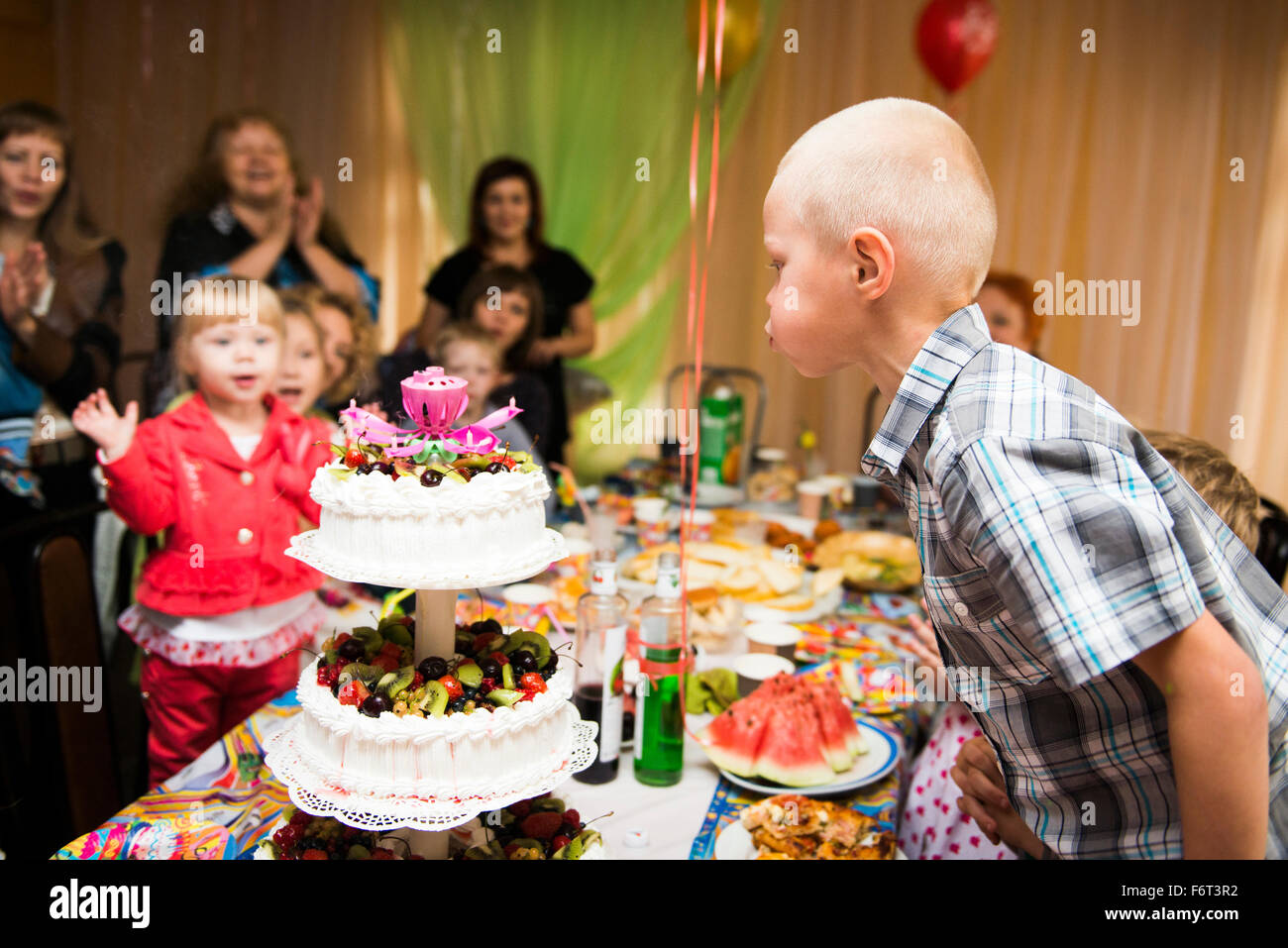 Kaukasische junge bläst Kerzen auf Geburtstagskuchen Stockfoto