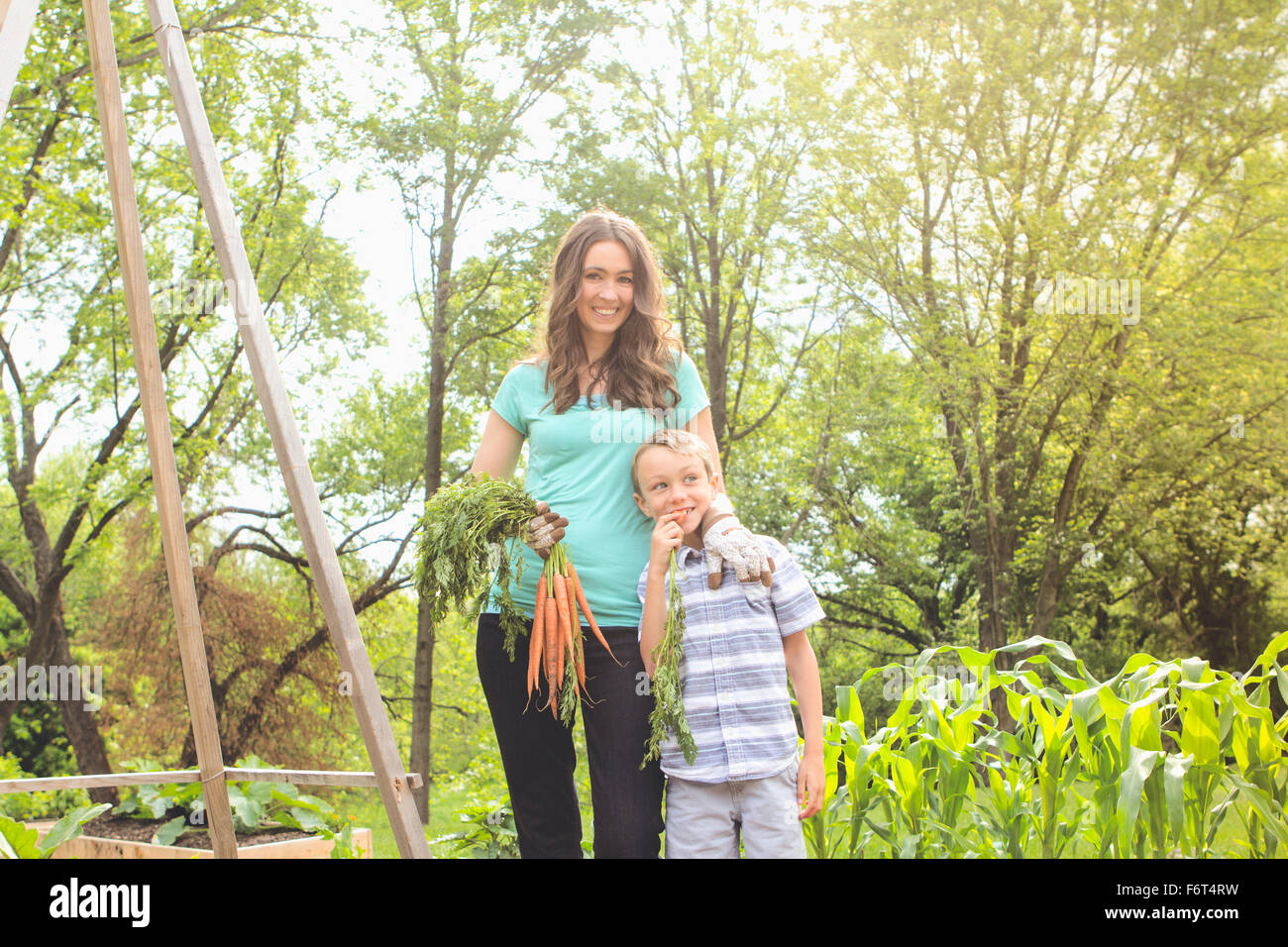 Kaukasische Mutter und Sohn halten Karotten im Garten Stockfoto