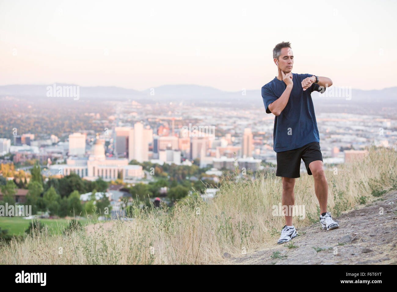 Gemischte Rassen Mann überprüfen Puls auf Hügel über Salt Lake City, Utah, Vereinigte Staaten von Amerika Stockfoto