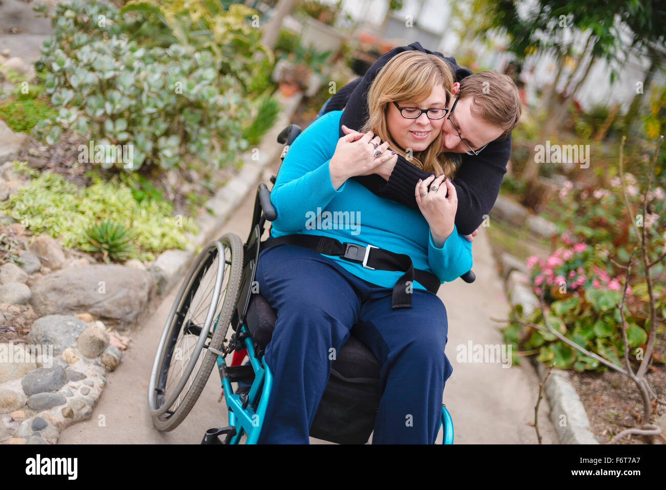 Mann umarmt querschnittsgelähmt Freundin im Garten Stockfoto