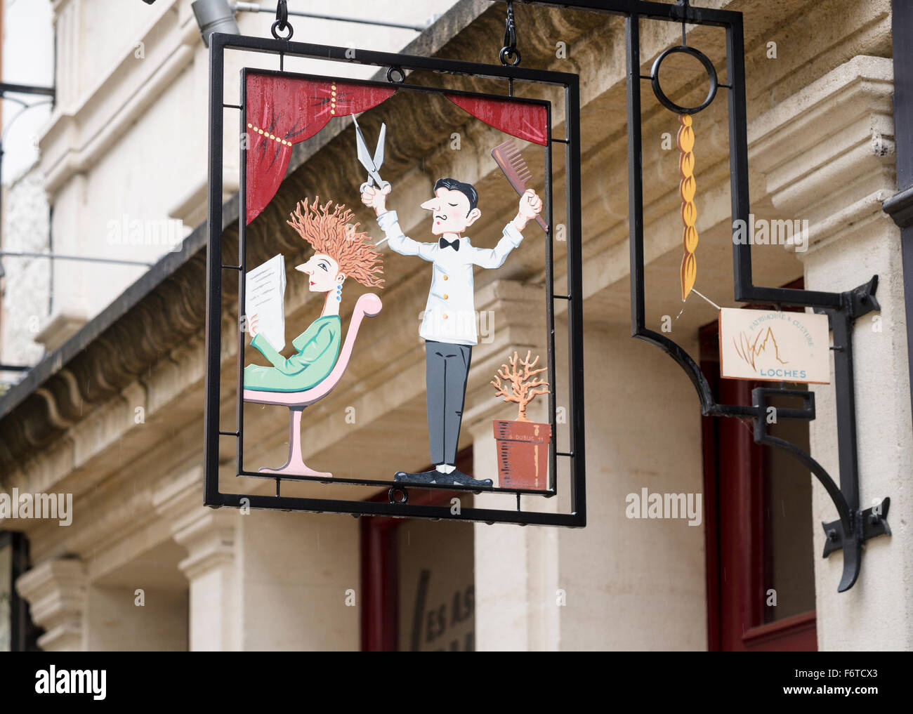 Ein Zeichen für einen Friseur-Shop in Loches. Ein Zeichen darstellen, ein Friseur und eine Frau mit Fly-away Haar wirbt eine Haare schneiden Stockfoto