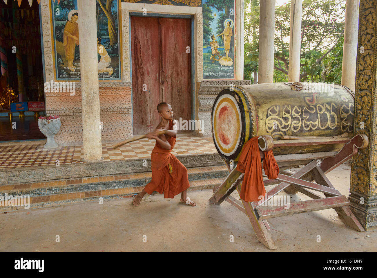 Junger Mönch schlägt eine Tempel Trommel um bedeuten Ruf zum Gebet in Kampong Phluk, Siem Reap, Kambodscha Stockfoto