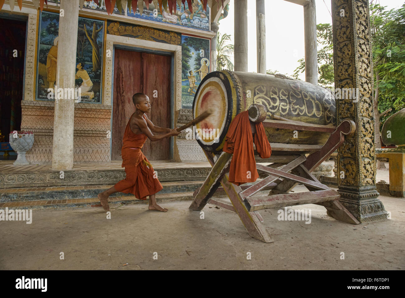 Junger Mönch schlägt eine Tempel Trommel um bedeuten Ruf zum Gebet in Kampong Phluk, Siem Reap, Kambodscha Stockfoto