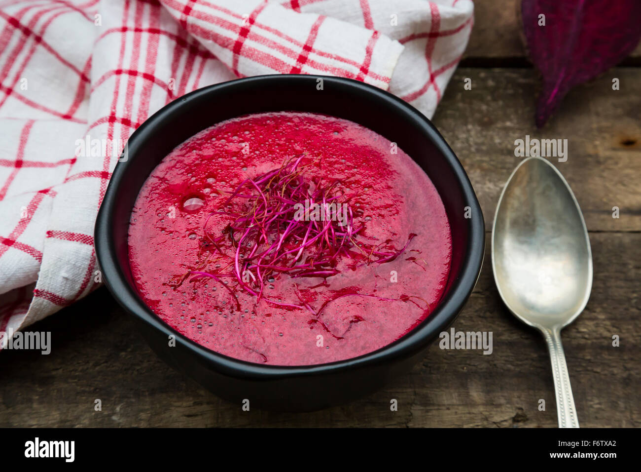 Rote Bete Suppe garniert mit rote Beete Sprossen auf dunklem Holz Stockfoto