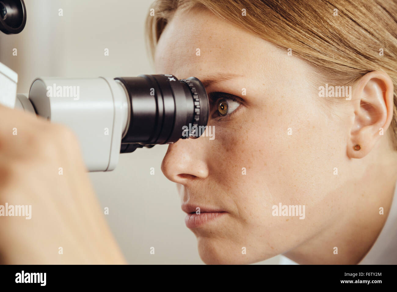 Profil von Ärztin Blick durch Operationsmikroskop Stockfoto