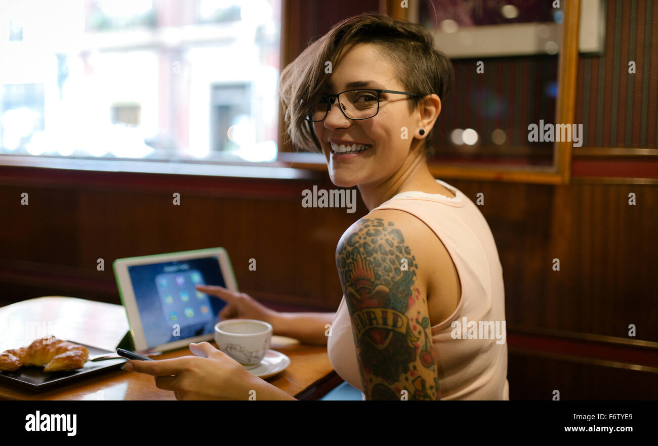 Porträt der tätowierte junge Frau sitzt in einem Café mit digital-Tablette Stockfoto