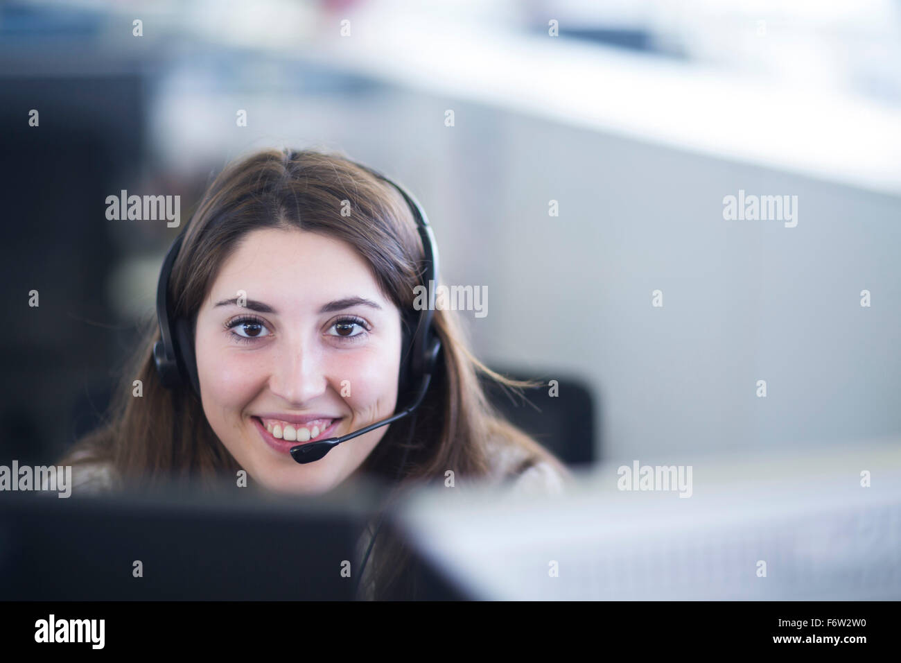 Porträt der lächelnde junge Frau mit Kopfhörer an ihrem Arbeitsplatz Stockfoto