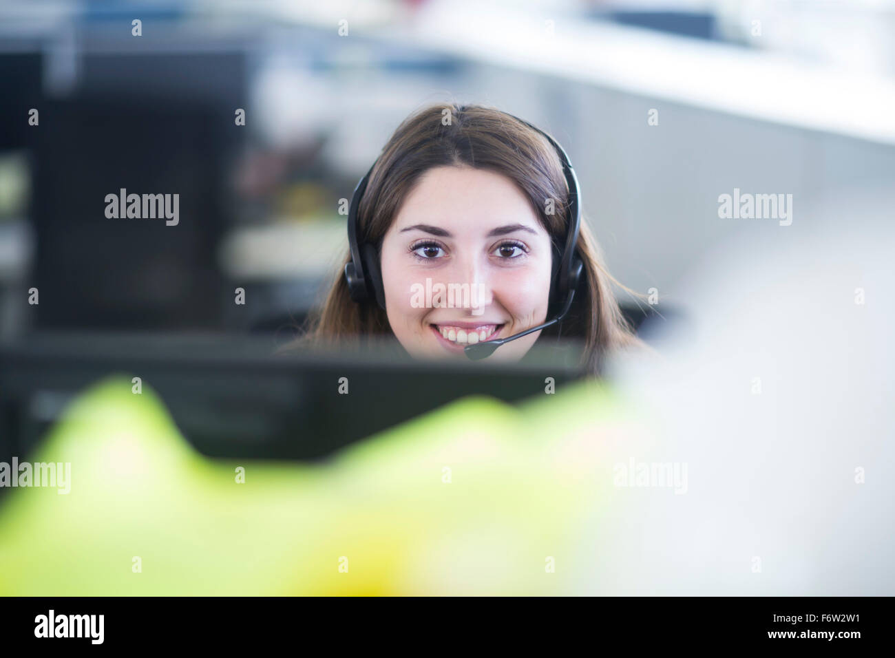 Porträt der lächelnde junge Frau mit Kopfhörer an ihrem Arbeitsplatz Stockfoto