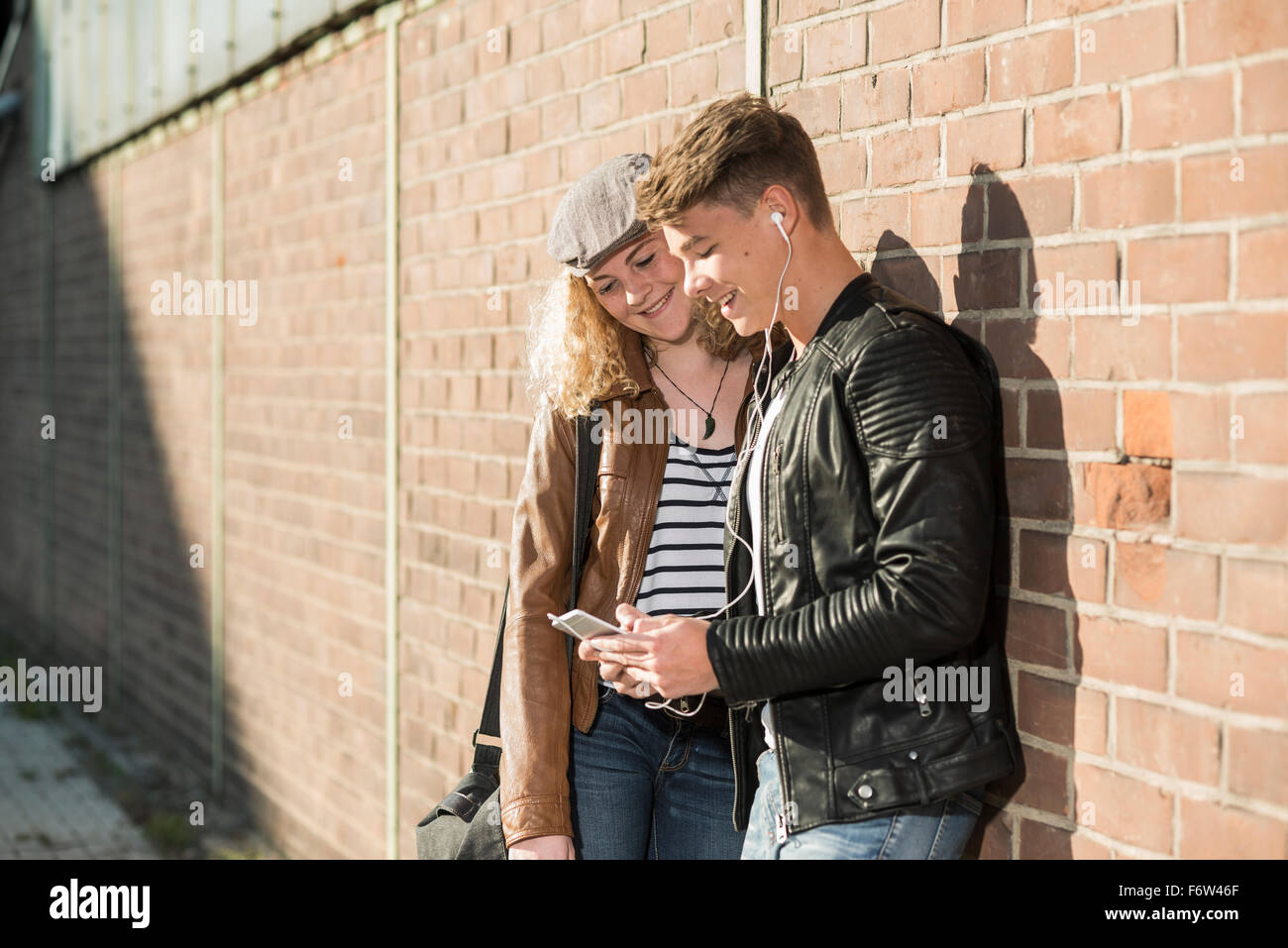 Entspannte junges Paar mit Handy und Ohrhörer im freien Stockfoto