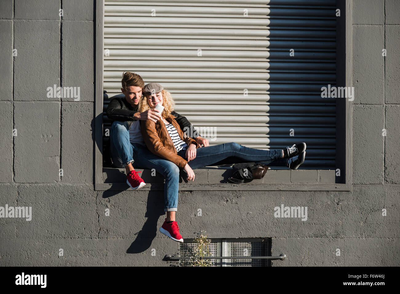 Entspannte junge Paar teilen Handy im freien Stockfoto
