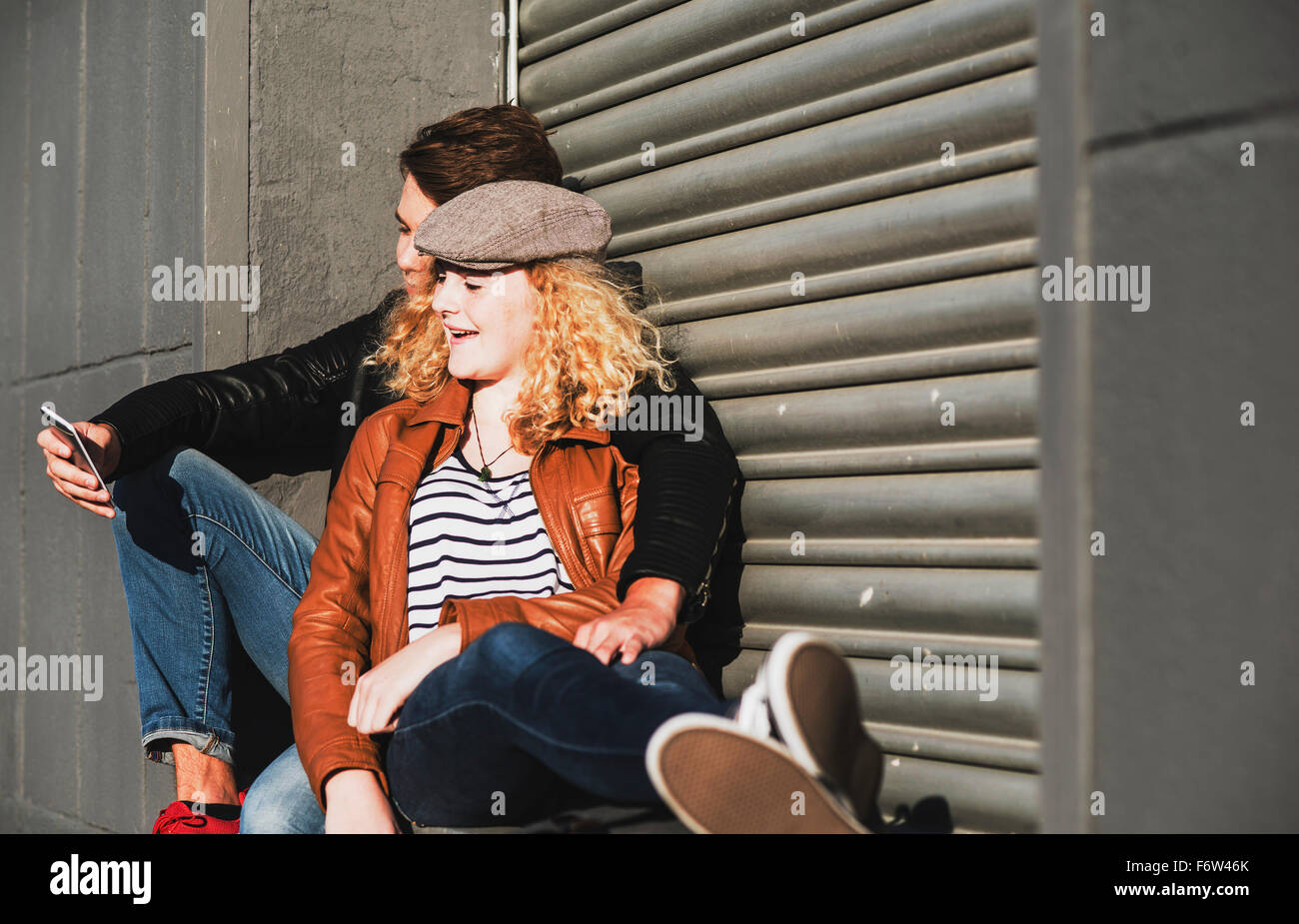 Entspannte junge Paar teilen Handy im freien Stockfoto