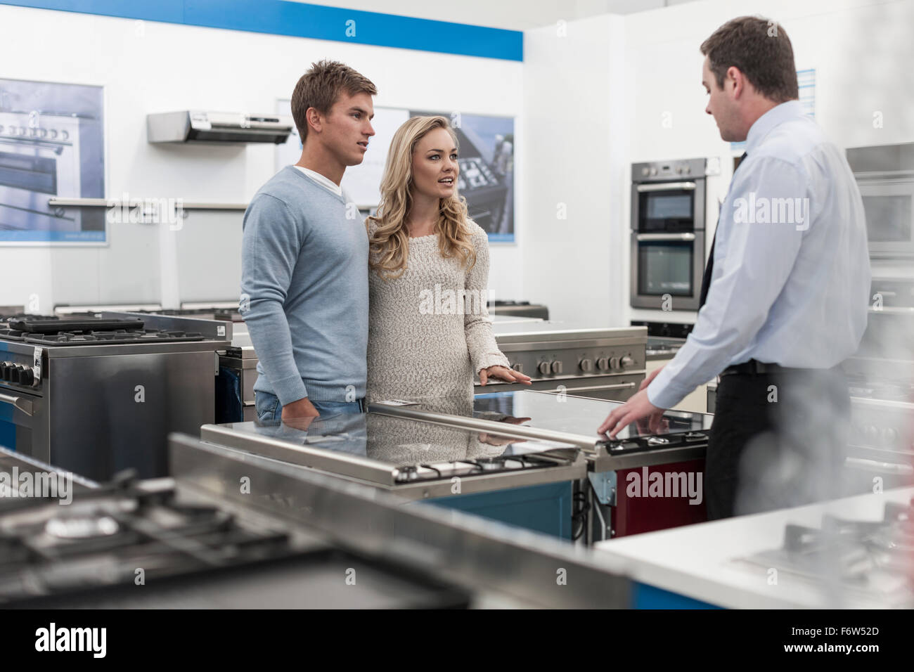 Verkäuferin im Gespräch mit junge Paar einkaufen Küchenausstattung Stockfoto