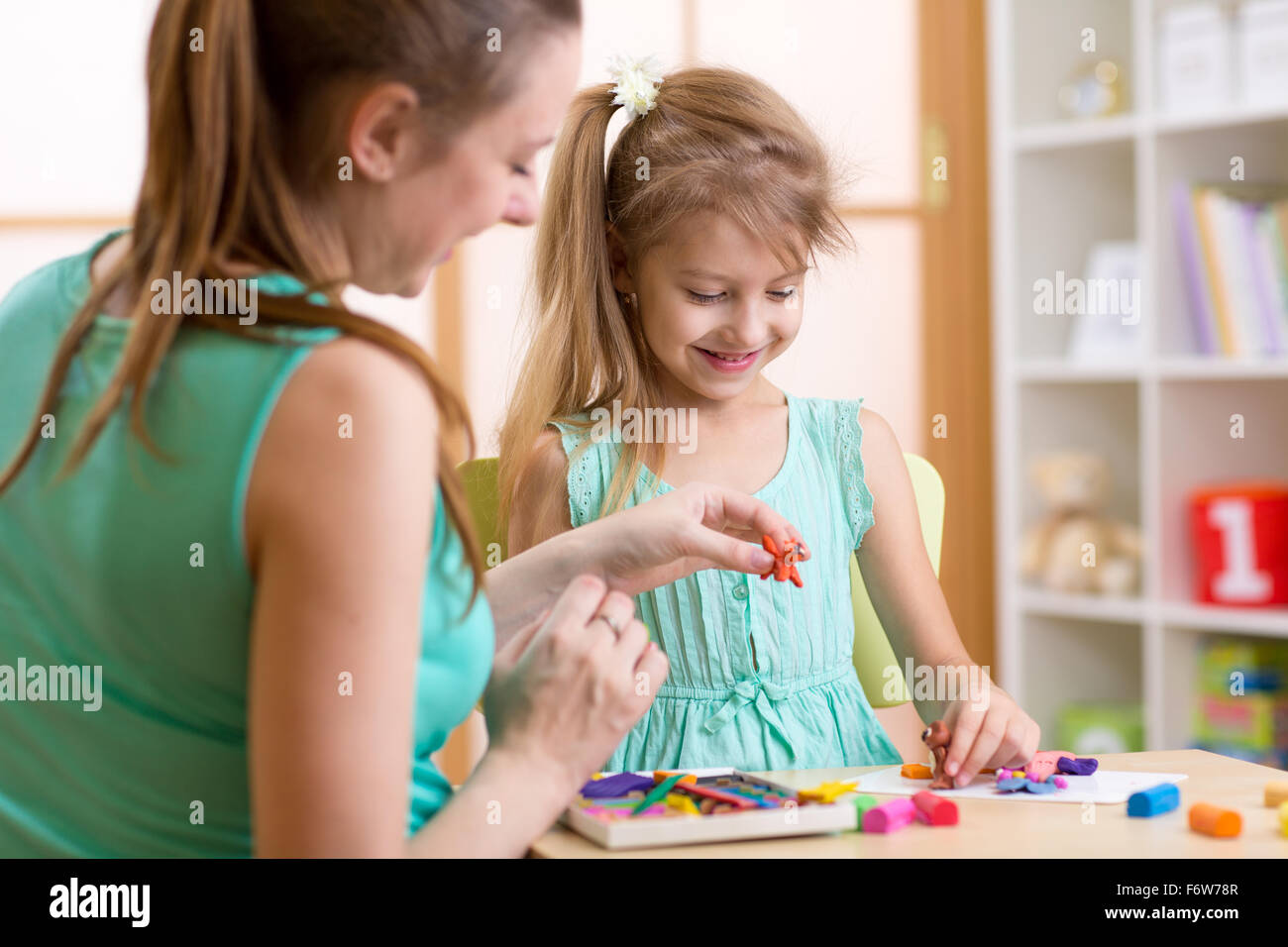 Glückliches Kind und Mutter am Tisch sitzen und mit bunten Ton Spielzeug spielen Stockfoto