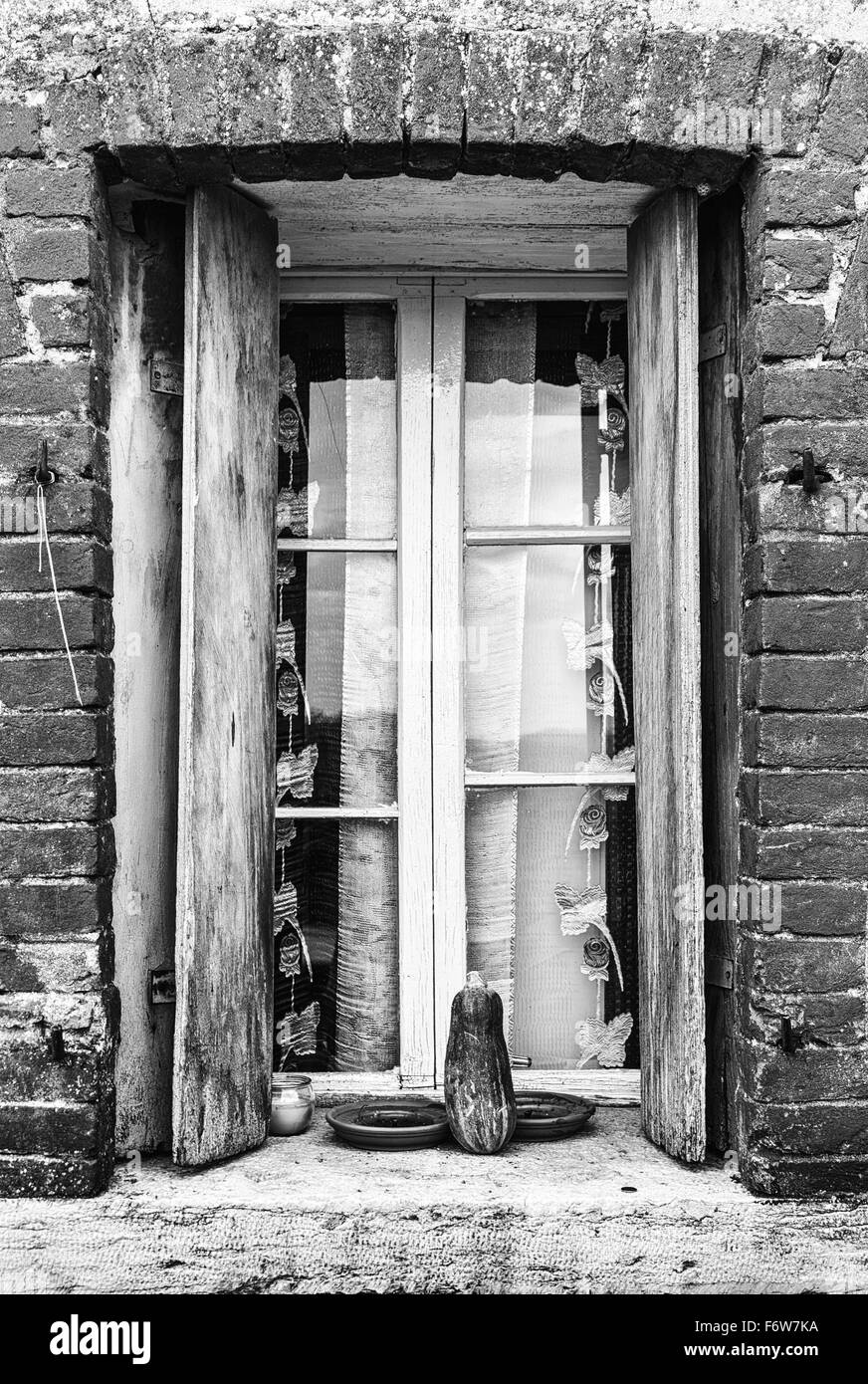 Fenster eines Bauernhauses mit Holzbalkonen und rotem Backstein Rahmen. Stockfoto