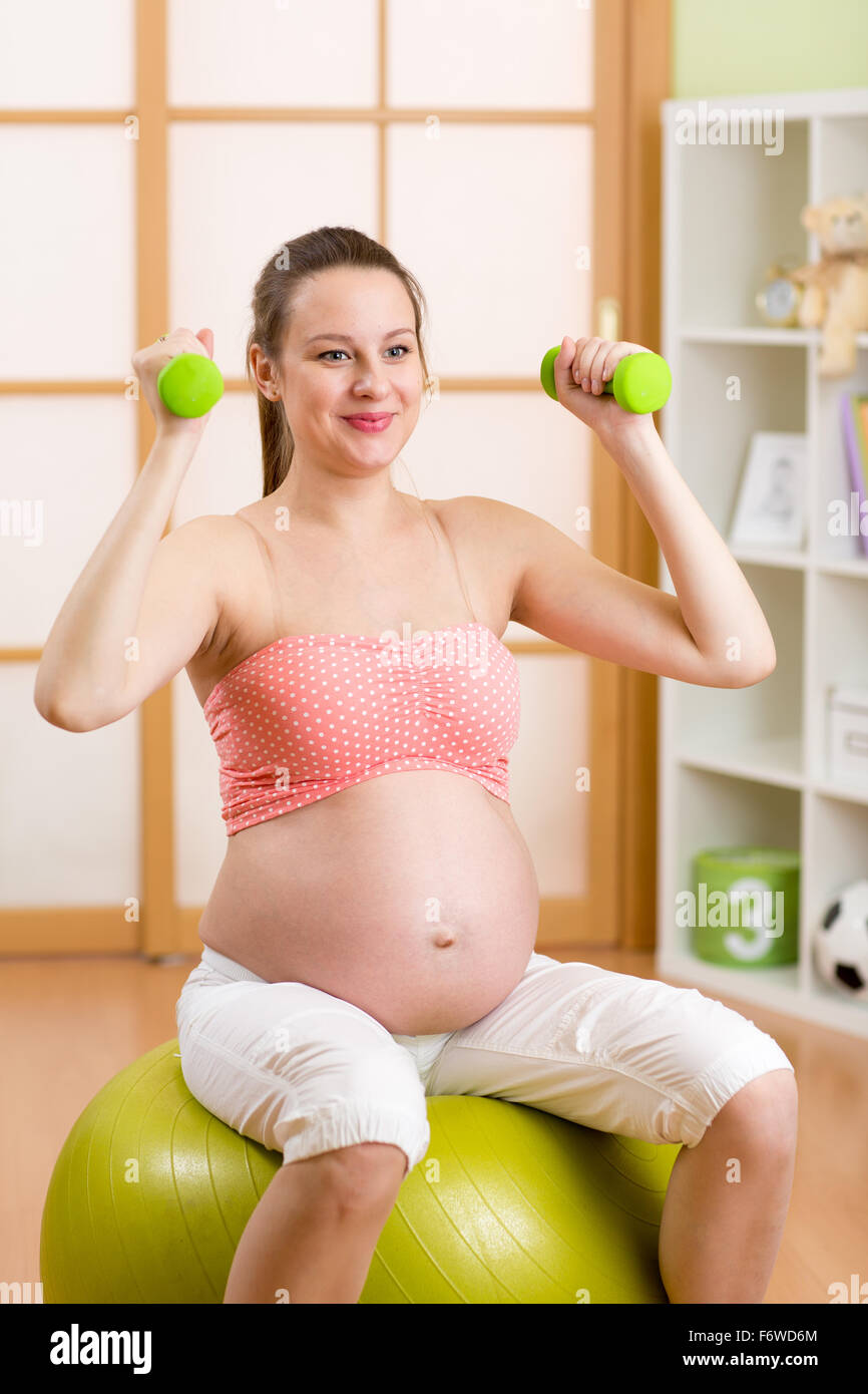 Schwangere Frau Fitness Übungen sitzen auf Gymnastikball Workout mit Hanteln Stockfoto