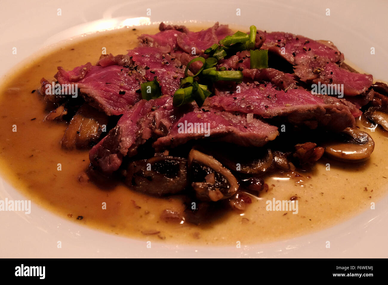 Ein Gericht aus gegrilltem Rindfleisch Runde schneidet serviert mit Pilzen und Frühlingszwiebeln Stockfoto