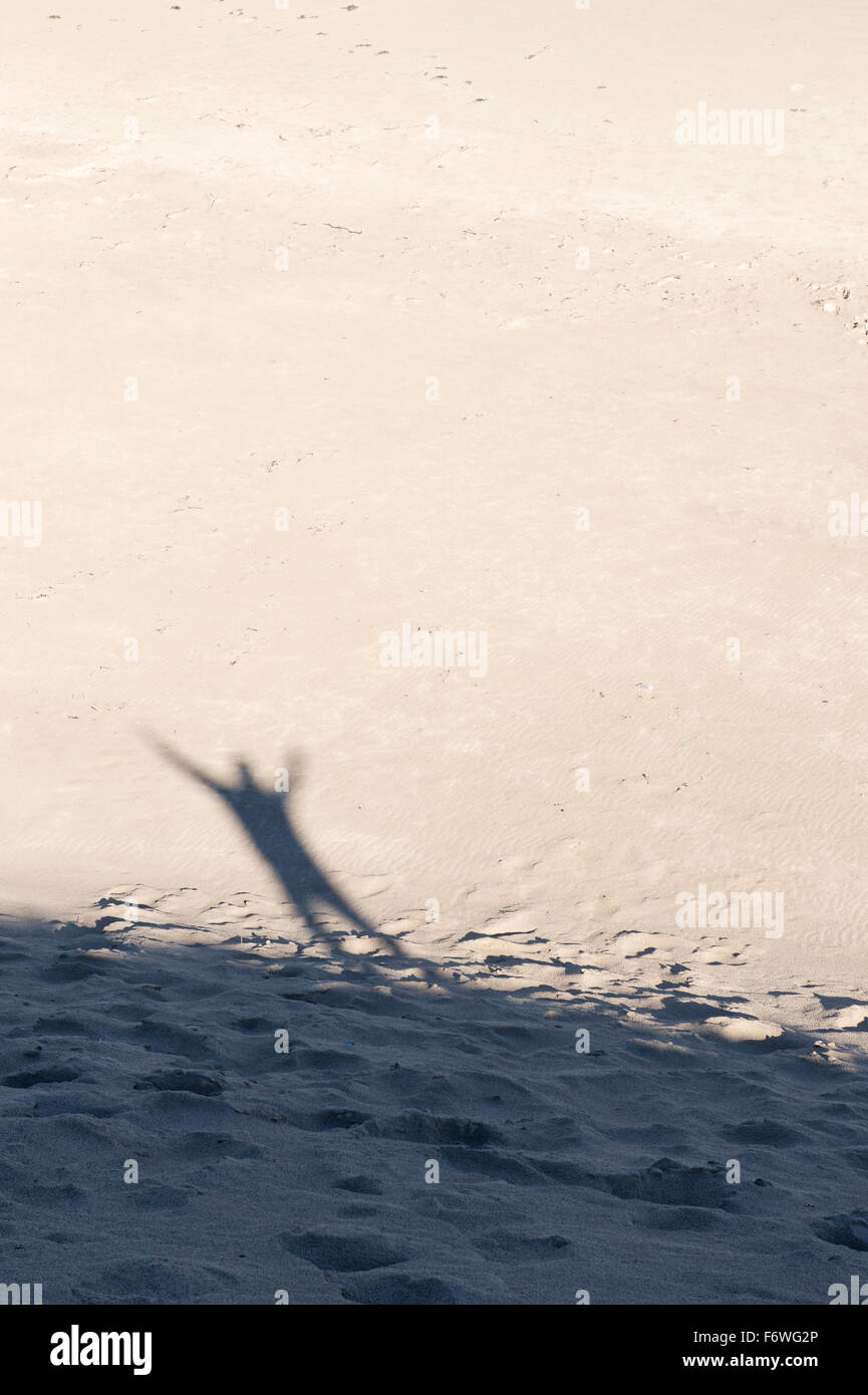 Schatten eines Mannes mit seinen Armen in der Luft auf einer Sanddüne am Strand. UK Stockfoto