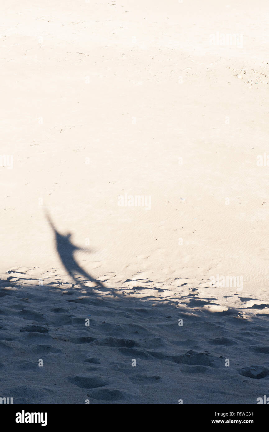 Schatten eines Mannes mit seinen Armen in der Luft auf einer Sanddüne am Strand. UK Stockfoto