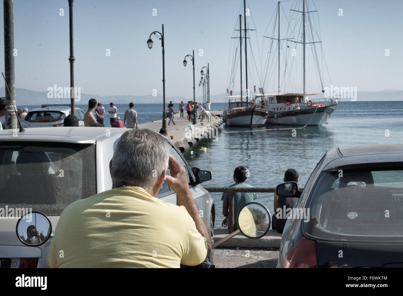 Griechischer Mann betrachtet die die Coast Guard Begleitung ein Boot aus der Türkei, die illegalen Einwanderer zu transportieren. Kos, Griechenland. September 2015 Stockfoto