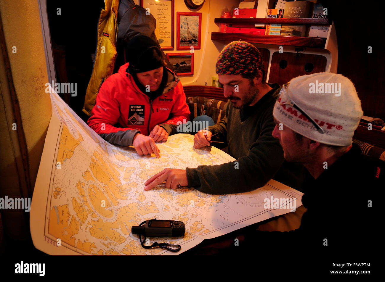 Drei Männer lesen eine Seekarte im Segelboot, Straße von Magellan, Chile Stockfoto