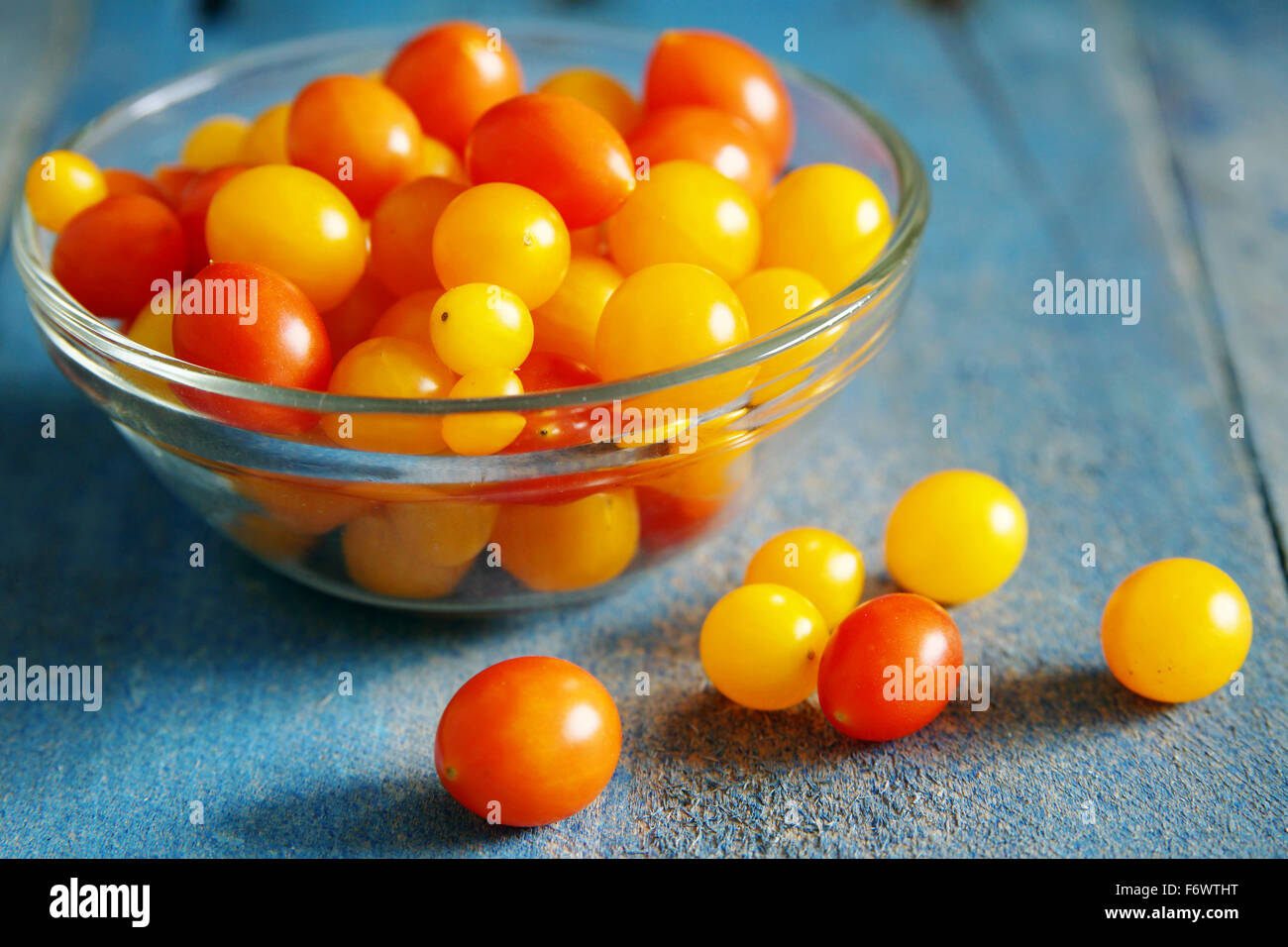 Rote und gelbe Tomaten bunten Süßigkeiten über alte Holz, Blaulicht Stockfoto