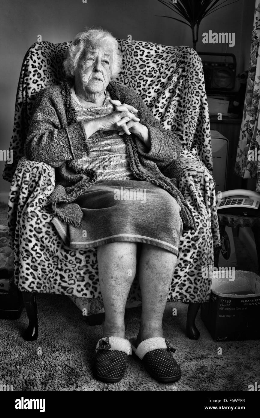 Eine alte Dame sitzt auf einem Stuhl Stockfoto