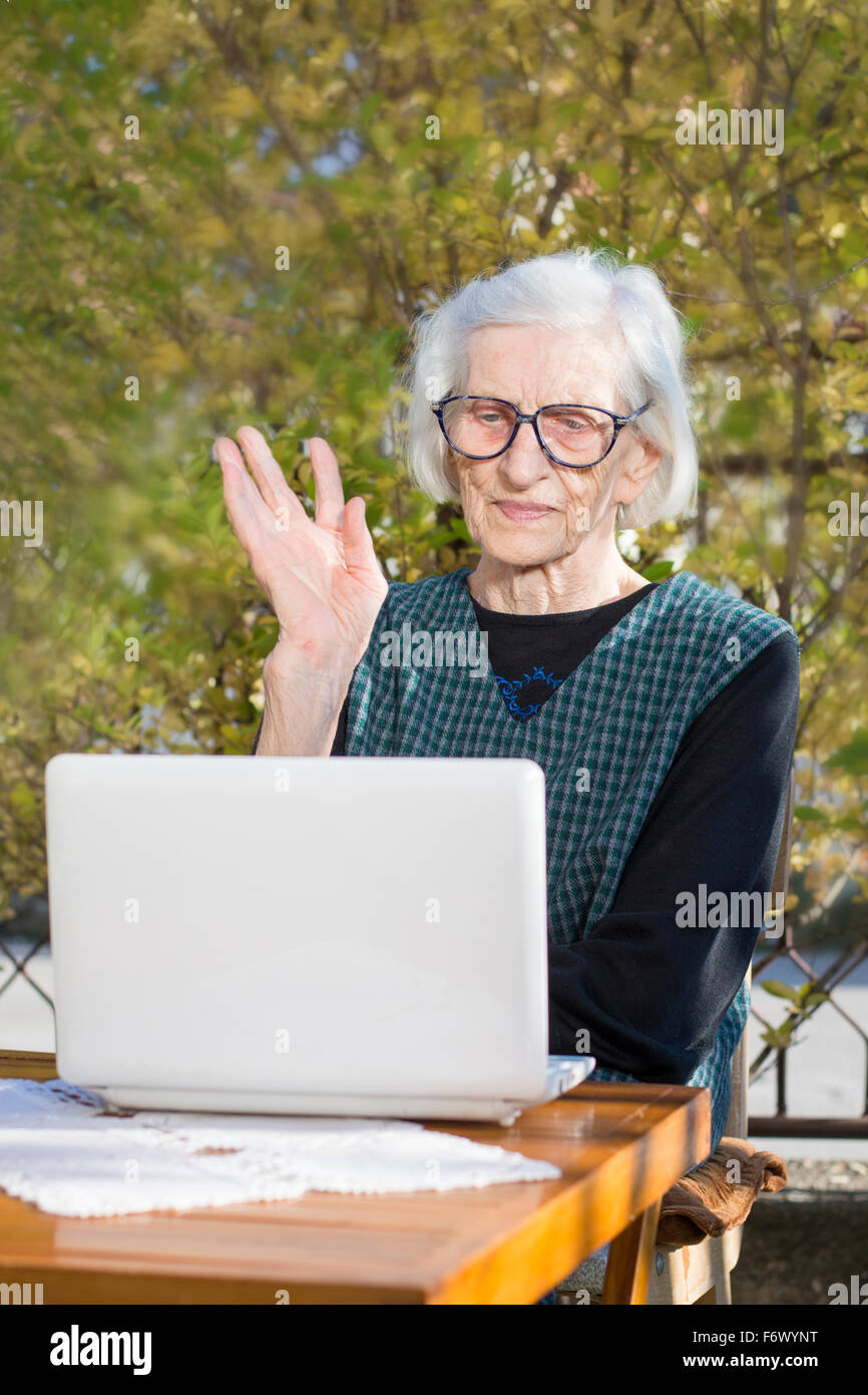 Ältere Frau, die einen Videoanruf auf einem Notebook-Computer im Hinterhof Stockfoto