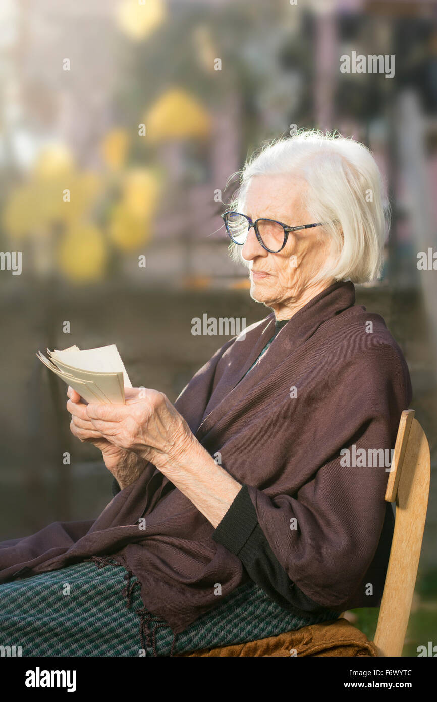 Oma mit Blick auf einige sehr alte Fotos im Hinterhof Stockfoto